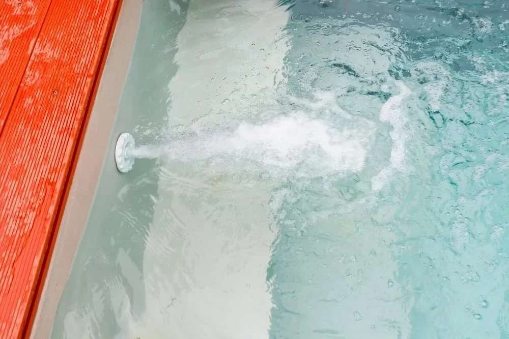 A jet of water spraying into a swimming pool.