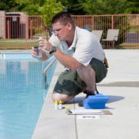 Service man checking chlorine, PH and other chemical levels in community pool