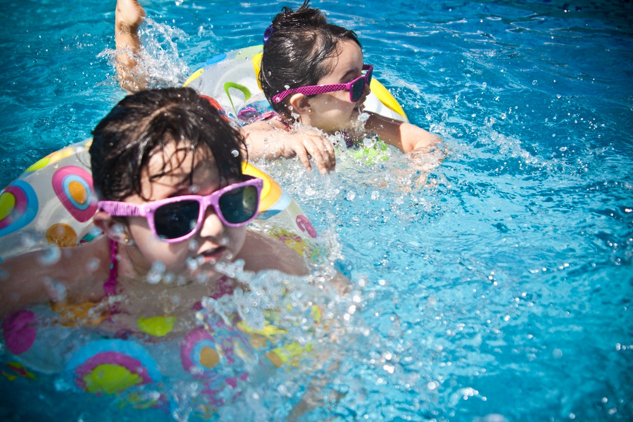 two kids in the pool wearing sunglasses