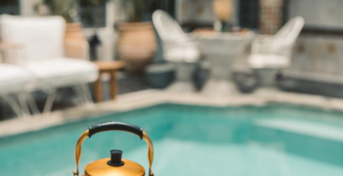 A gold kettle sitting next to a pool