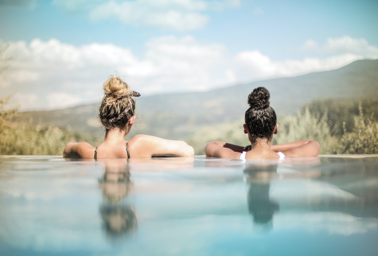 Two women in the infinity pool with mountains in the back