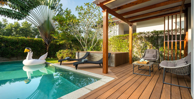 A wooden deck with chairs and a swimming pool.